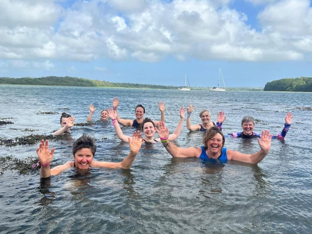 A group of people waving while swimming at Out & Wild Festival