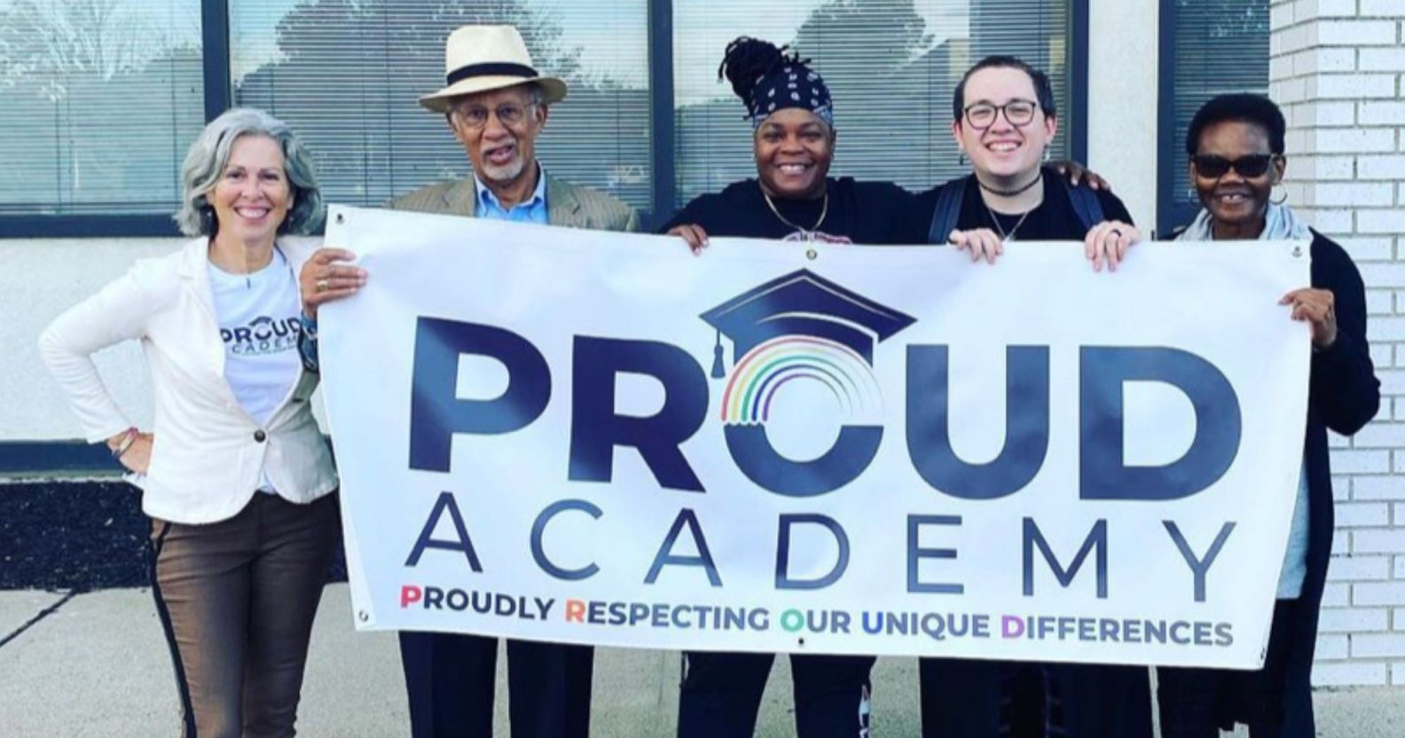 A photo showing lesbian teacher Patricia Nicolari (left), with members of the PROUD Academy board holding a sign saying "PROUD Academy"