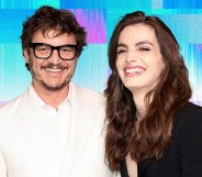 A graphic showing cut-out images of actor Pedro Pascal wearing a white shirt and glasses standing next to his trans sister Lux Pascal who is dressed in a black top. Both are smiling and are set against a background made up of trans flag colours blue and pink