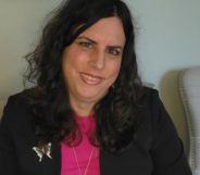 Photo of Dr Tiffany Najberg wearing a black suit jacket over a pink top as she sits on a chair