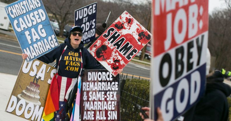 A member of the Westboro Baptist Church holding up various hateful signs.