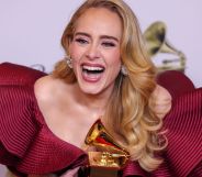 Adele wears a red dress as she laughs and holds a golden award after the Grammys