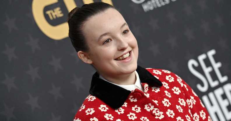 Photo of actor Bella Ramsey wearing a red and white floral-pattern shirt smiling at a press event