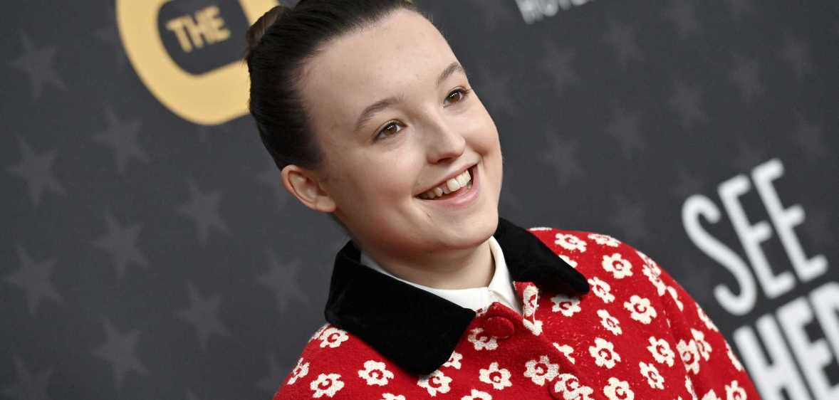 Photo of actor Bella Ramsey wearing a red and white floral-pattern shirt smiling at a press event
