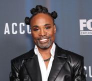 Billy Porter with his hair in bantu knots, wearing a white shirt and leather jacket