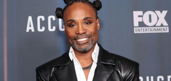Billy Porter with his hair in bantu knots, wearing a white shirt and leather jacket