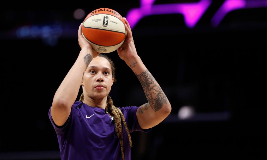 Brittney Griner wears a purple top as she shoots a white and orange basketball during a WNBA game warm-up