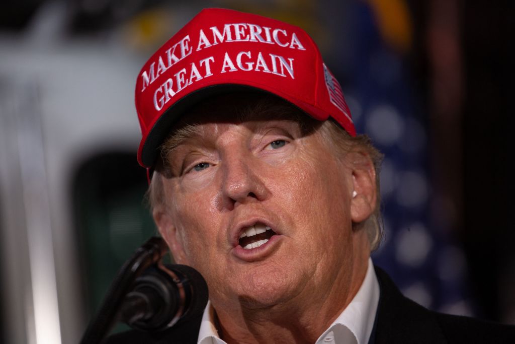 Donald Trump wearing a "Make America Great Again" cap while speaking at a rally.