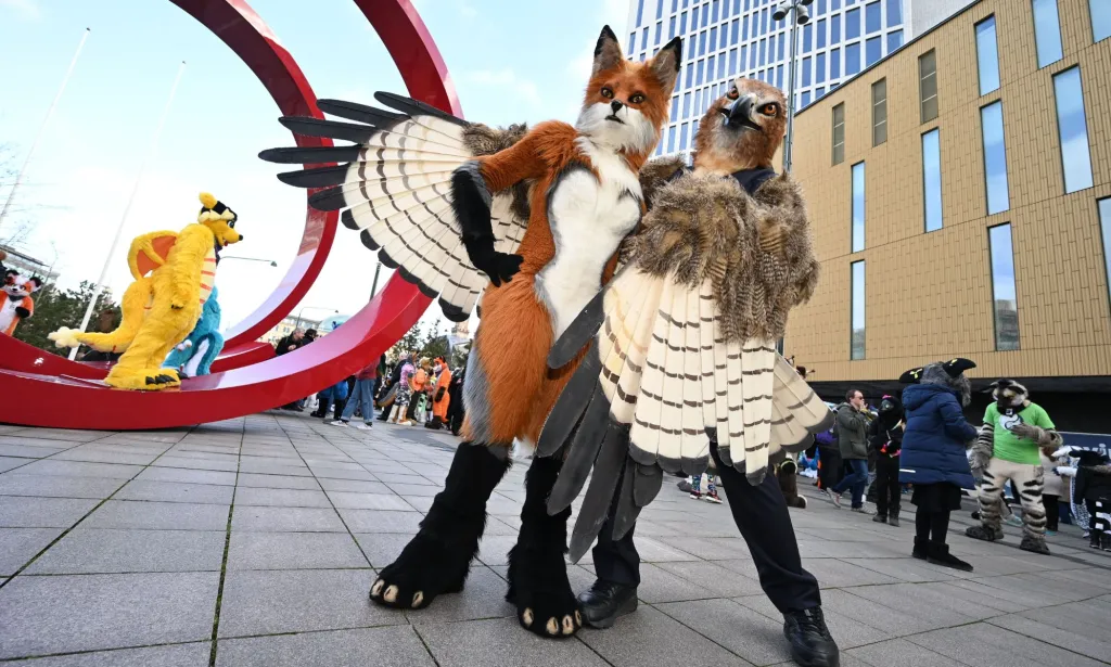 People dressed as a fox and an eagle pose as they attend a fuzzcon parade at a furry event