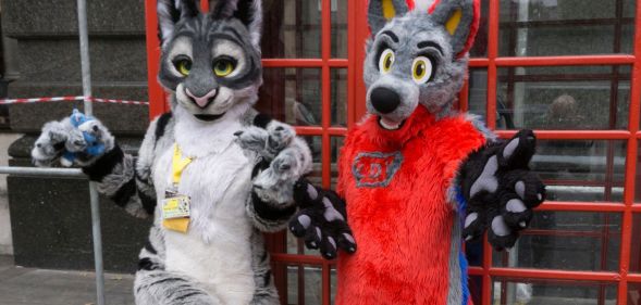 Two people, who are part of the furry community, dress in colourful fursuits as they pose outside in London for a photograph