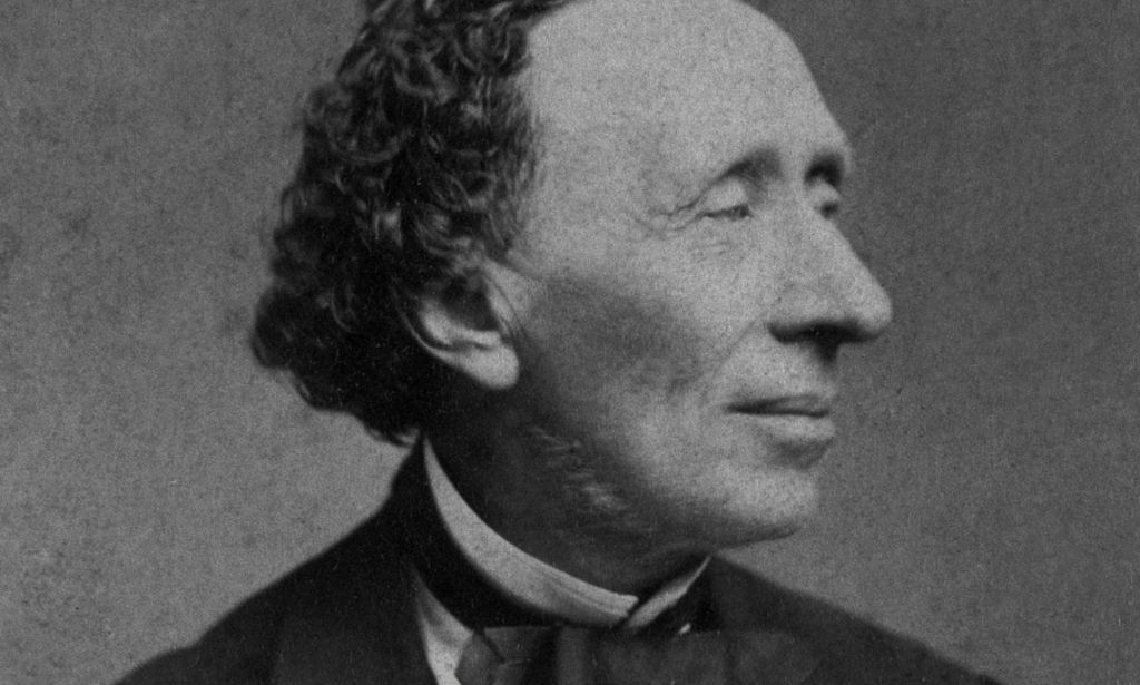A black and white photograph of Danish author Hans Christian Andersen wearing a white shirt and dark clothing as he poses for the camera