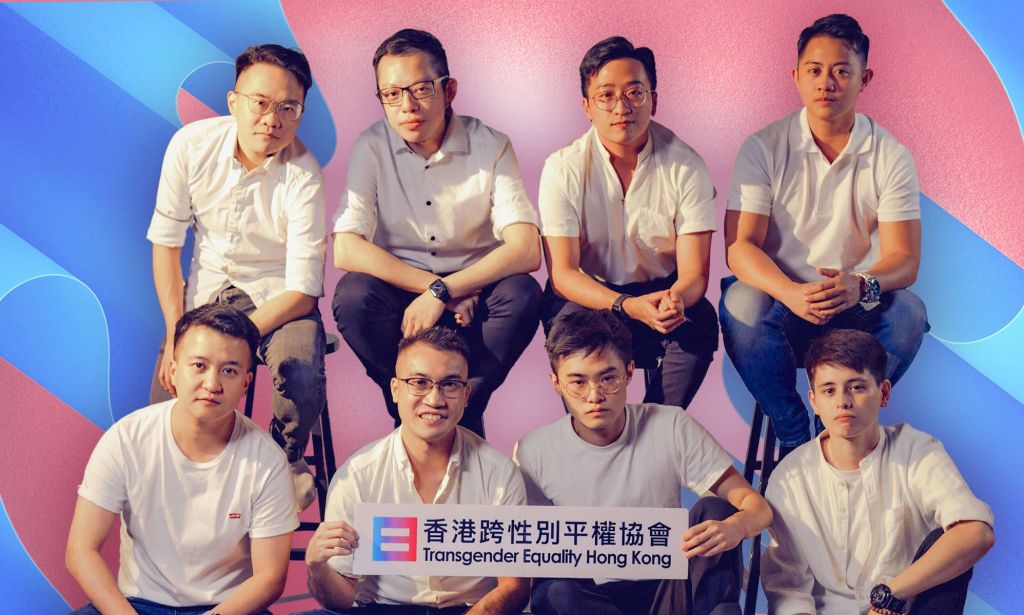 Trans activist Henry Edward Tse sits alongside other trans men while holding up a sign reading Trans Equality Hong Kong with blue and pink designs in the background