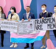 Henry Edward Tse and allies stand together with a variety of signs including a mock up of Tse's ID card with an 'F' gender marker to highlight the trans activist's legal battle in Hong Kong