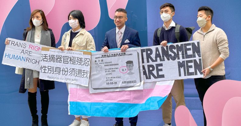 Henry Edward Tse and allies stand together with a variety of signs including a mock up of Tse's ID card with an 'F' gender marker to highlight the trans activist's legal battle in Hong Kong