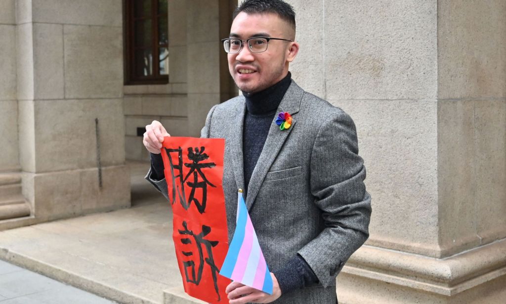 Trans activist Henry Tse poses with a sign which translates to 'Legal Victory' outside the Court of Final Appeal in Hong Kong