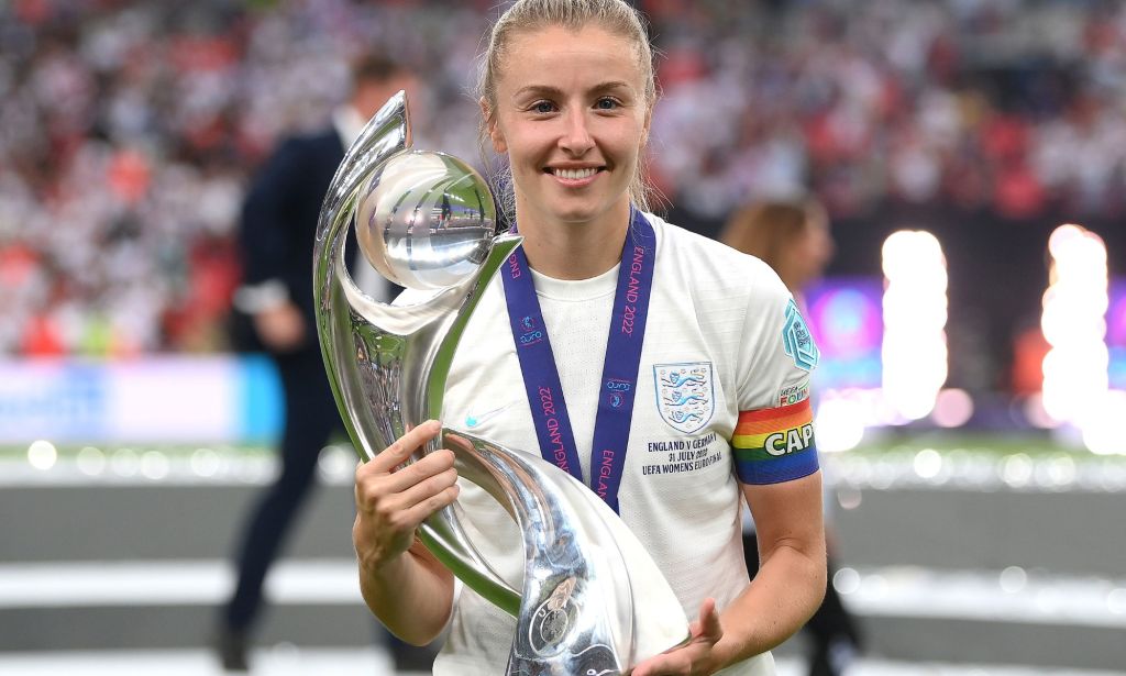 England's Leah Williamson, who is wearing a white football uniform and rainbow armband, lifts the UERA Women's Euro 2022 trophy after the Lionesses victory