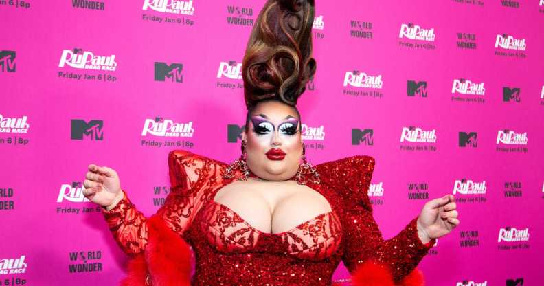 A photo of drag queen Mistress Isabelle Brooks from RuPaul's Drag Race season 15 wearing an over-the-top red dress as she poses for the cameras at an MTV publicity event