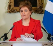 Nicola Sturgeon in a red suit speaking at a lecturn