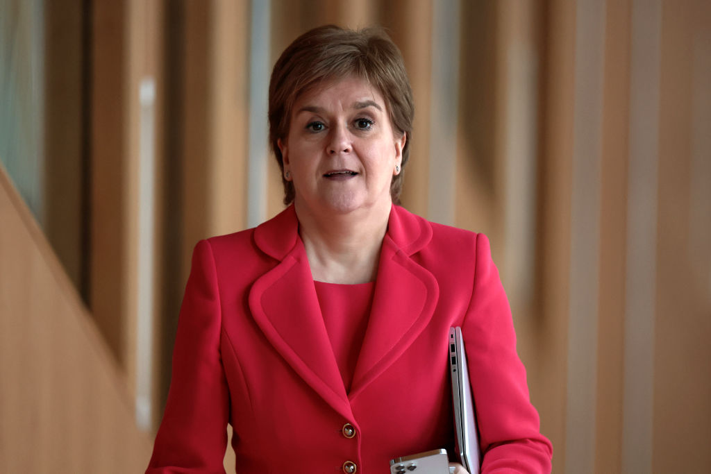 Nicola Sturgeon arrives to Scottish Parliament in February 2023. She is wearing a red suit.