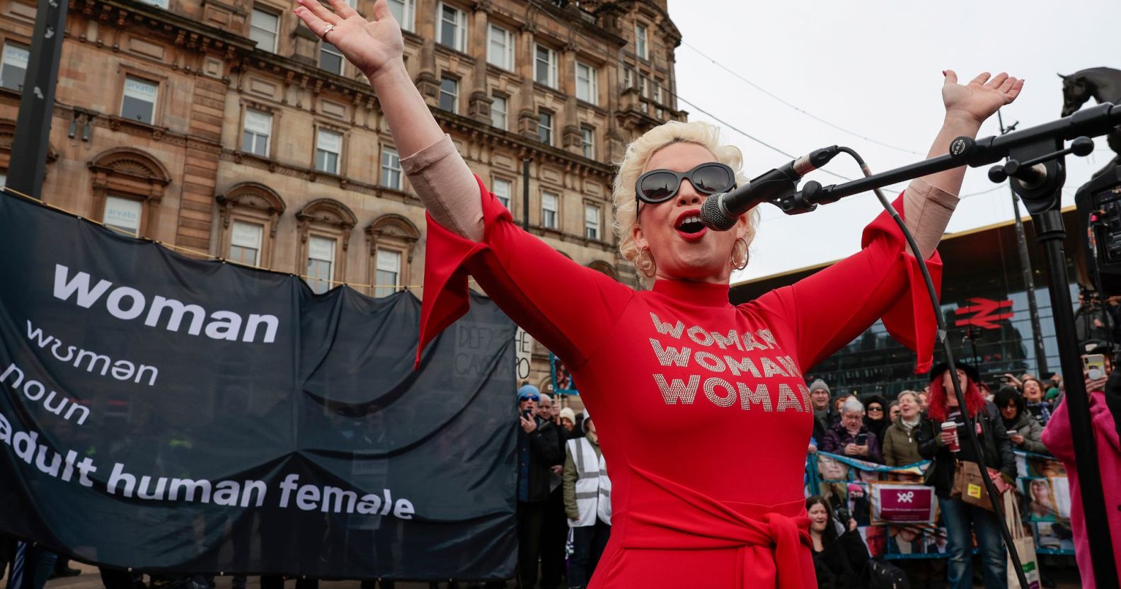Anti-trans activist Kellie-Jay Keen, also known as Posie Parker, wears a red outfit as she speaks at an event which was met with counter-protesters