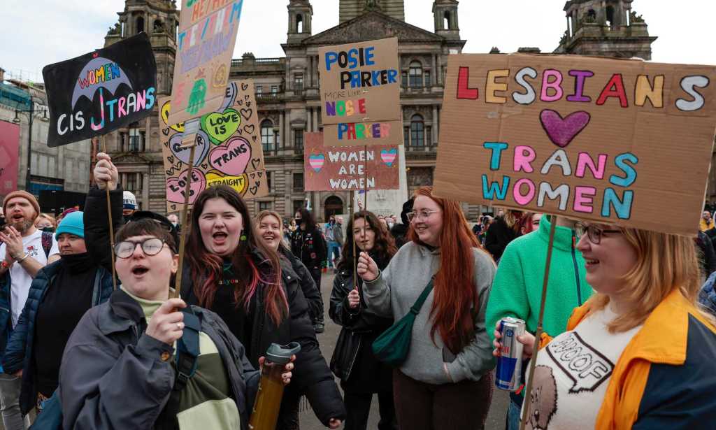A photo showing trans rights protesters in Glasgow holding placards with messages saying "Lesbians love trans women"