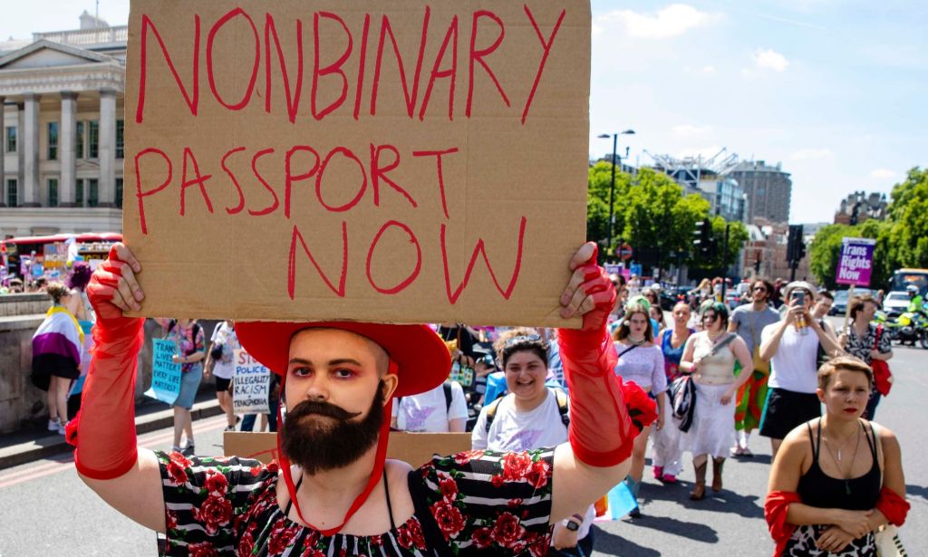 A person holds up a sign reading 'non-binary passport now' during a protest