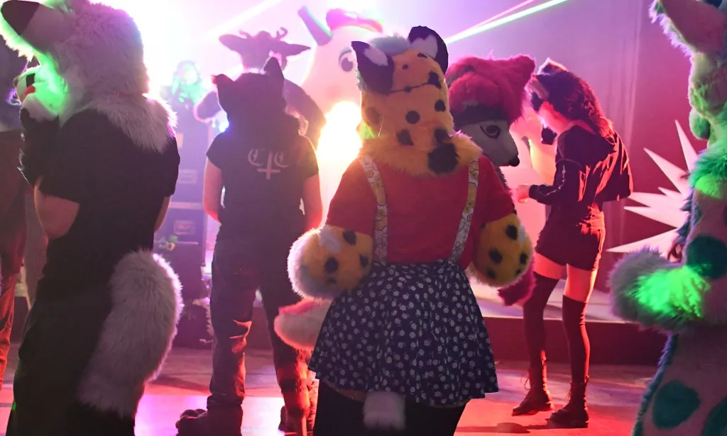 Reskell, an LGBTQ+ furry, dances at a furry event while surrounded by other furries