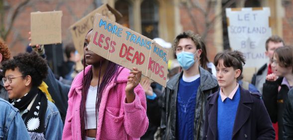 A person holds up a sign reading 'More trans kids, less dead kids' during a trans rights protest