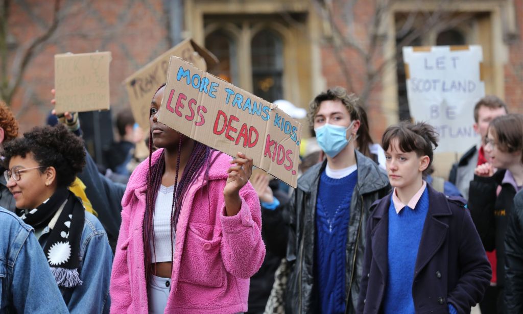 A person holds up a sign reading 'More trans kids, less dead kids' during a trans rights protest