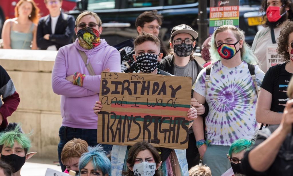 A person holds up a sign reading "It's my birthday and all I want is trans rights" during a protest