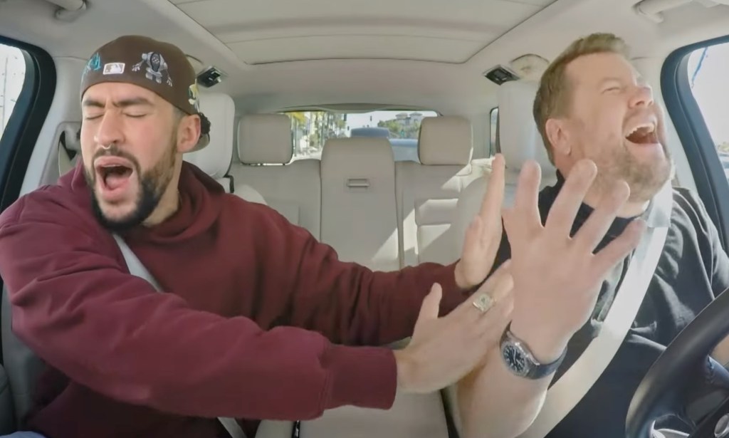 Bad Bunny and James Corden singing and gesturing passionately in the front of a car