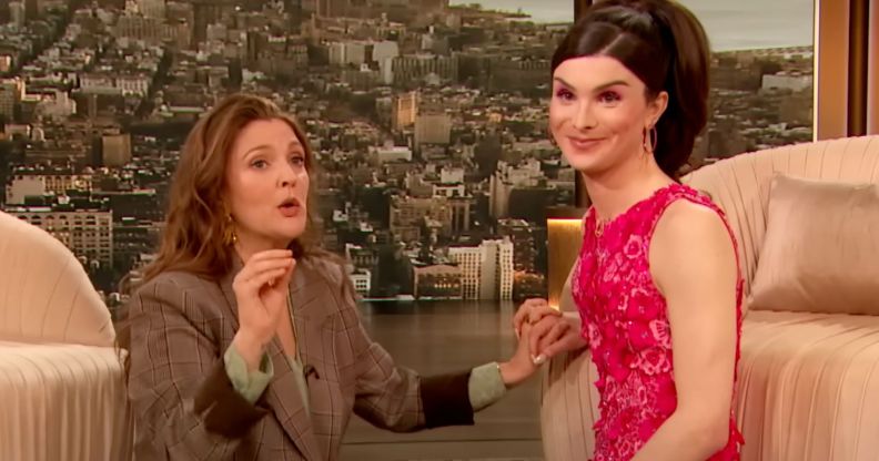 Dylan Mulvaney holds hands with Drew Barrymore on The Drew Barrymore Show.