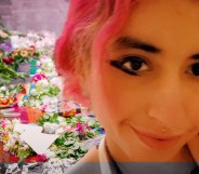 A photo of Eden Knight, a young woman with a bright pink bob and winged eyeliner, in front of flowers