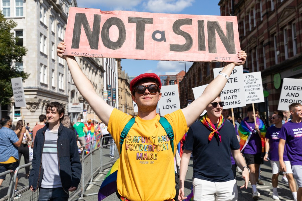 A person at Manchester Pride holding a sign that reads 'Not a Sin'