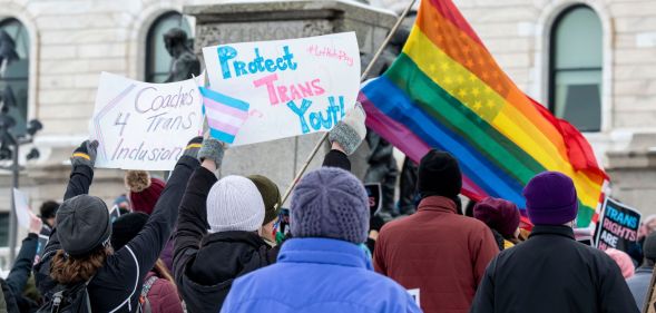 Minnesota activists wave flags and signs of LGBTQ+ pride.