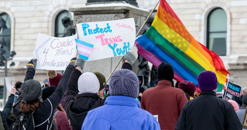 Minnesota activists wave flags and signs of LGBTQ+ pride.