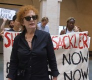 Nan Goldin at a protest, stood in front of banners