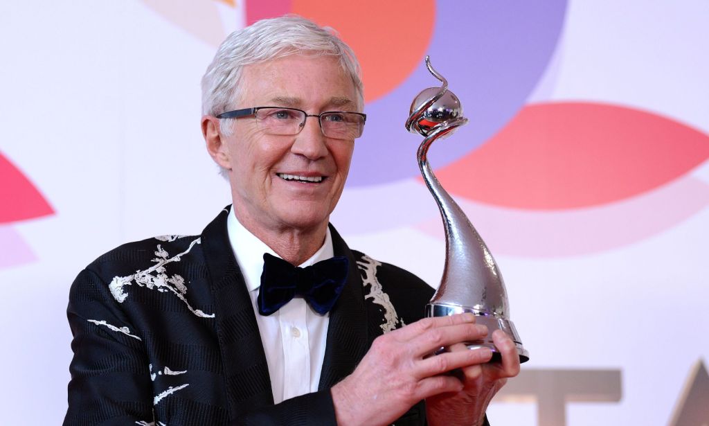 Paul O'Grady wearing a black suit and bow tie and carrying his National Television Award.