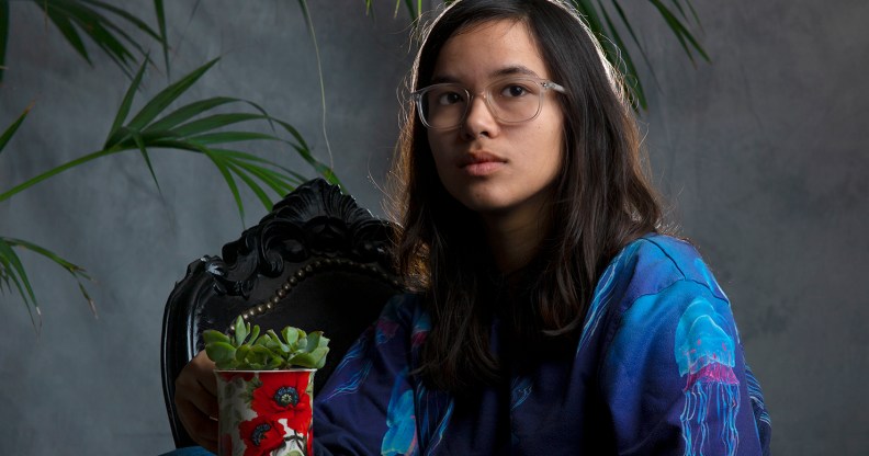 Pippa sitting, holding a potted succulent on their knee