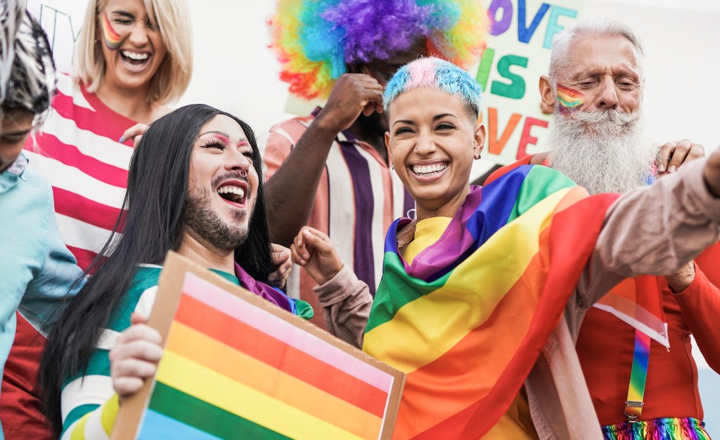 A group of LGBTQ people celebrating Pride and waving rainbow flags