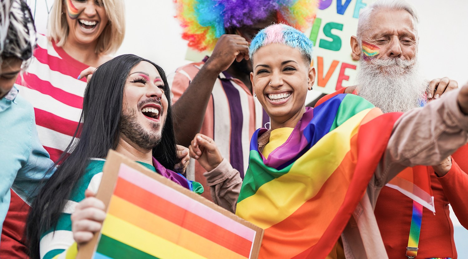 A group of LGBTQ people celebrating Pride waving rainbow flags