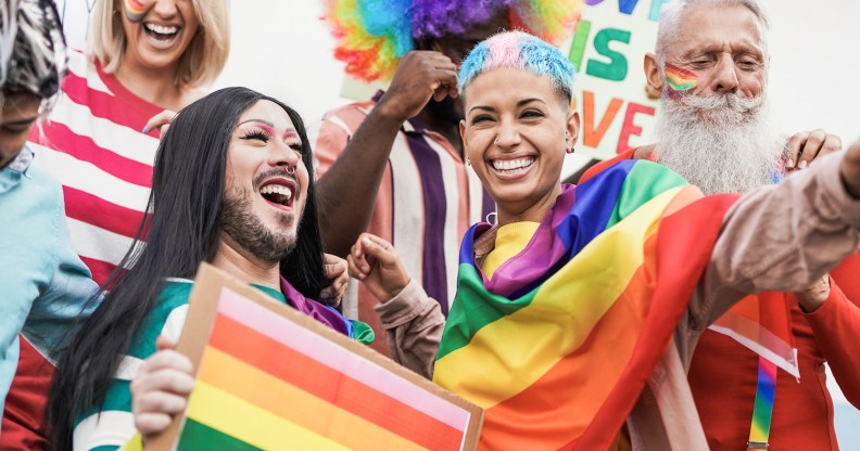 A group of LGBTQ people celebrating Pride and waving rainbow flags