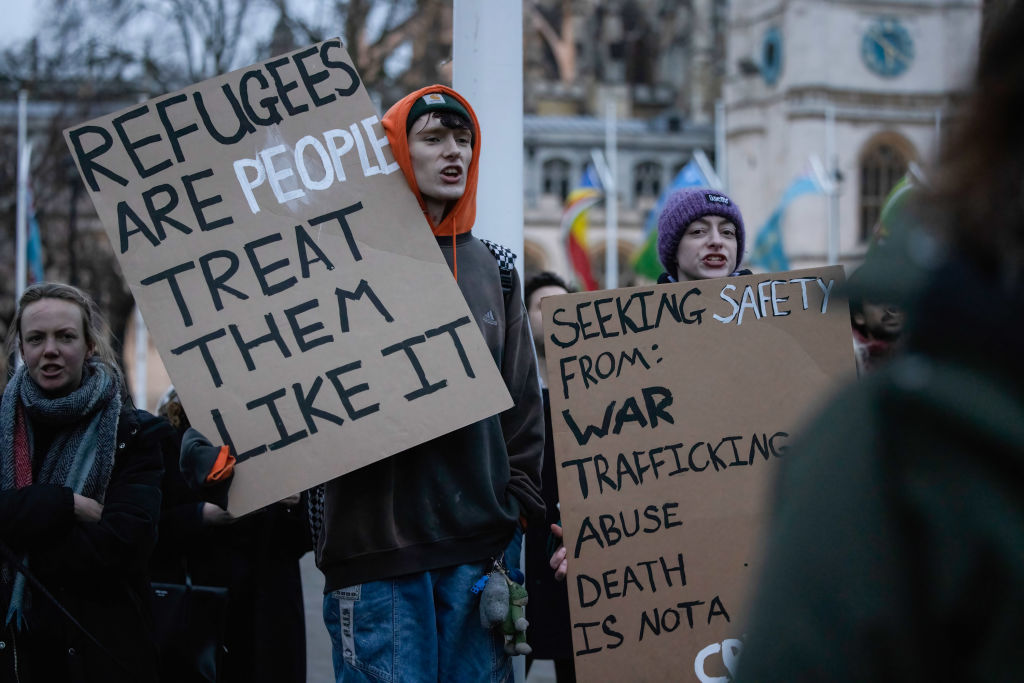 Protesters are seen holding placards expressing support for refugees during a rally at Parliament Square. 