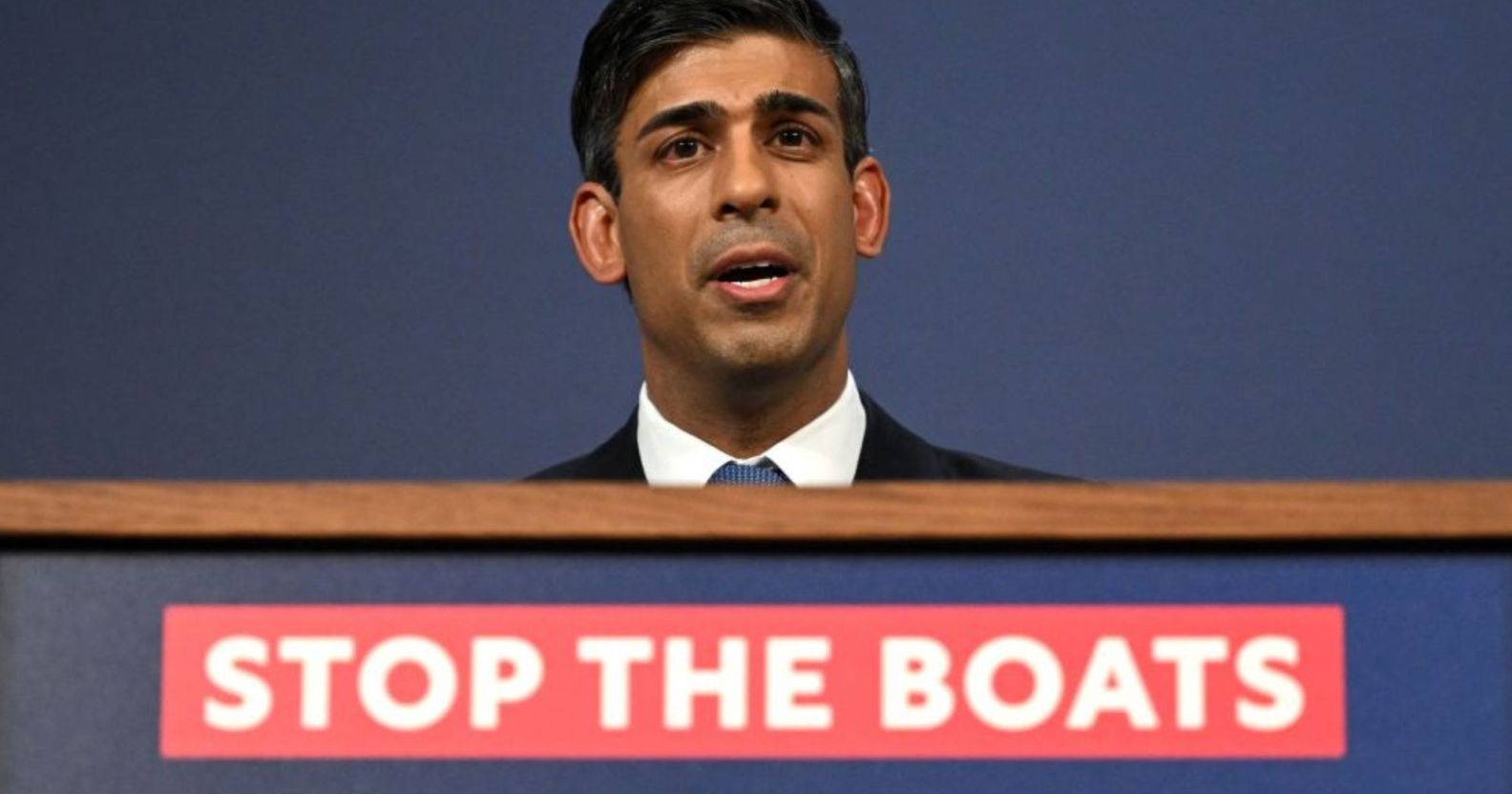 Rishi Sunak announcing the Illegal Migration Bill at a podium with the message "stop the boats".