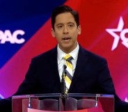 Daily Wire host Michael Knowles stands in front of a red and blue background reading "CPAC"