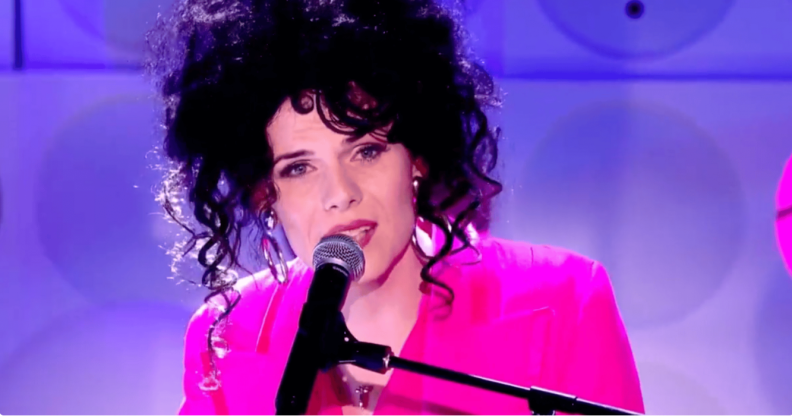 Jordan Gray wears a pink suit as she sings into a microphone during her Channel 4 Friday Night live performance