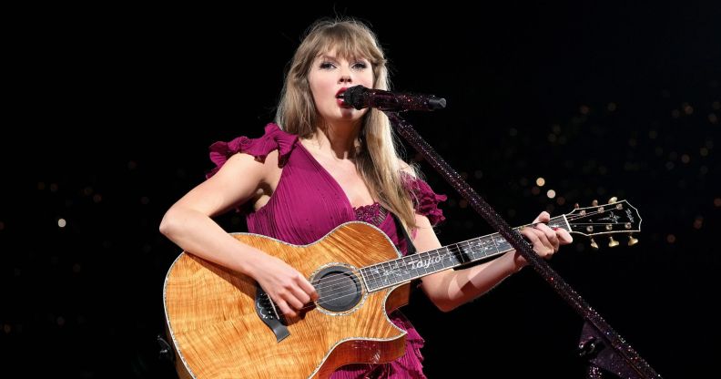 Taylor Swift in a dark pink gown singing with her guitar on the Eras Tour.