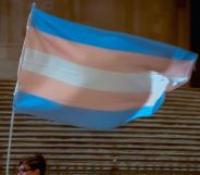 A person holds up a trans flag.