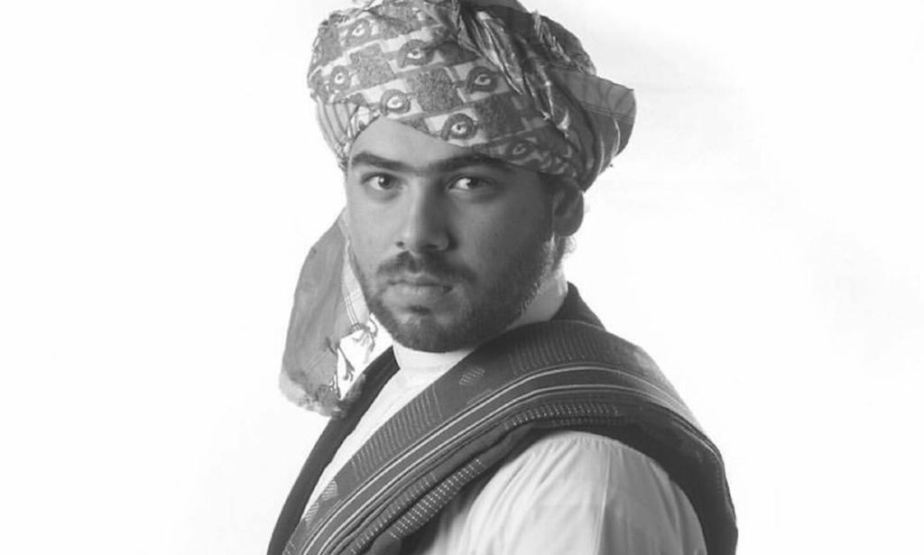 A black and white photo of Wajeeh Gay Lion, an openly gay activist from Saudi Arabia, wearing a head covering and other traditional Saudi clothing