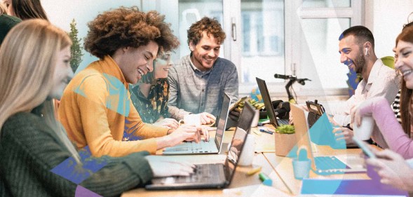 A group of young employees are gathered around a conference table.